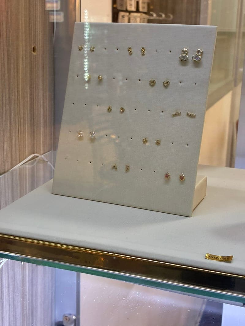 Brincos em ouro 18k expostos em display do ateliê